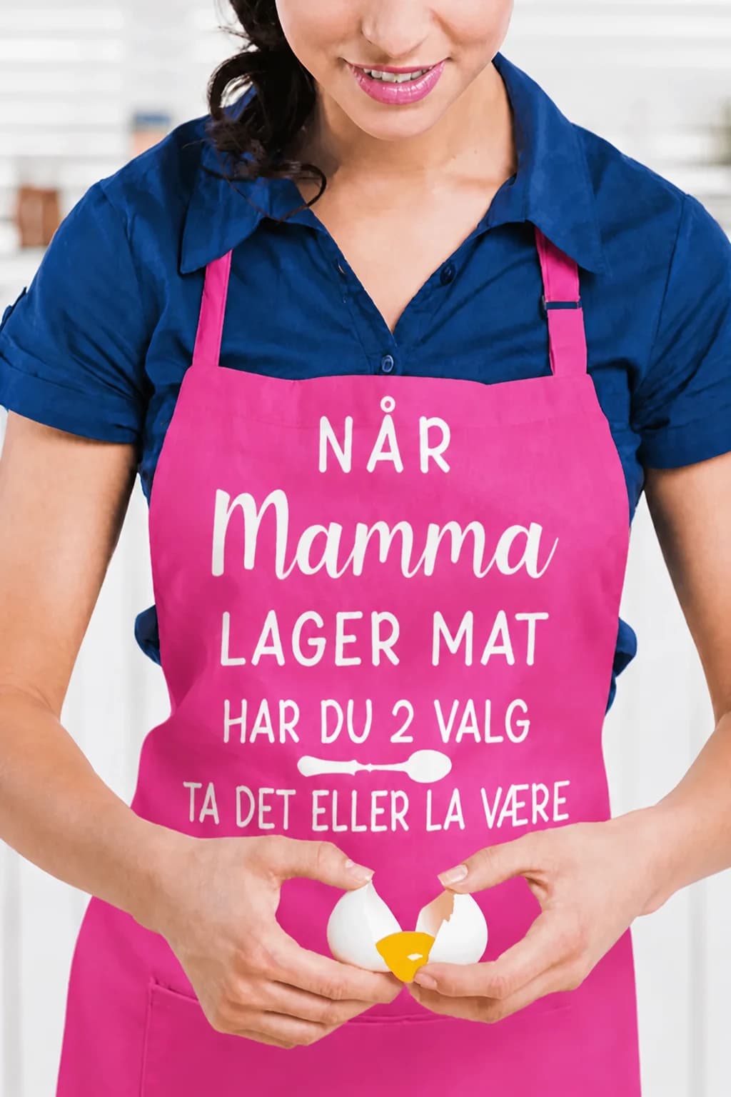 Rosa forkle med hvit tekst «NÅR MAMMA LAGER MAT, HAR DU 2 VALG: TA DET ELLER LA VÆRE» og skje