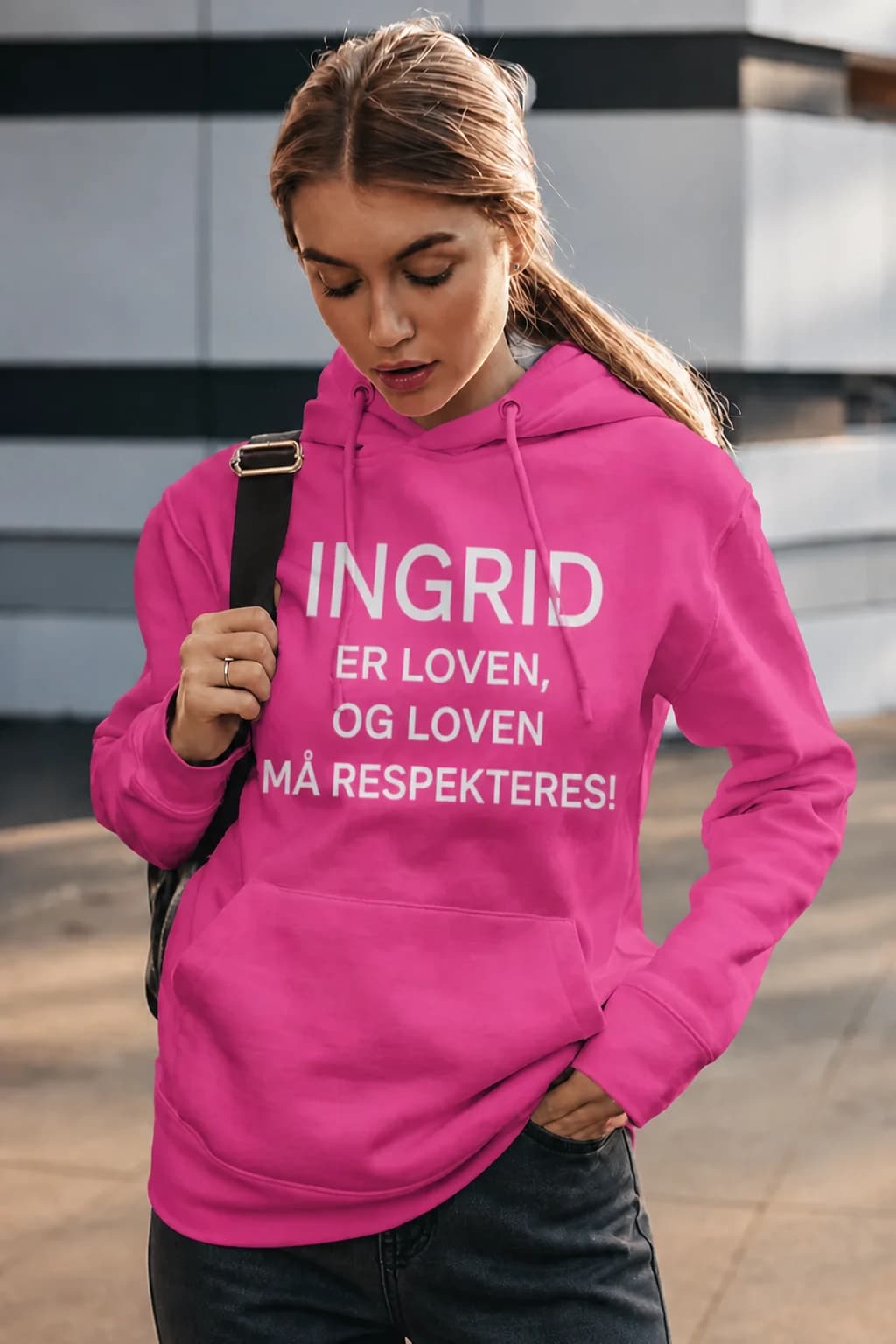 Mørk rosa hettegenser med hvit tekst «INGRID ER LOVEN, OG LOVEN MÅ RESPEKTERES!» på ung kvinne