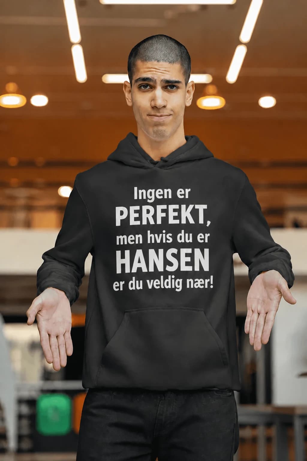 Mann i grå hettegenser med tekst «Ingen er PERFEKT, men hvis du er HANSEN, er du veldig nær!» og navn