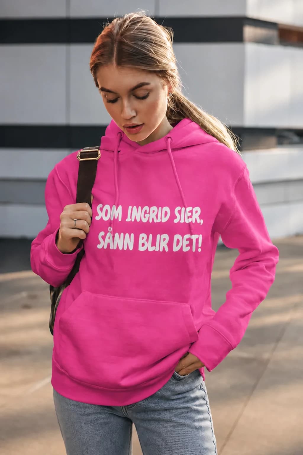Kvinne i rosa hettegenser med hvit tekst «SOM INGRID SIER, SÅNN BLIR DET!», personlig med navn