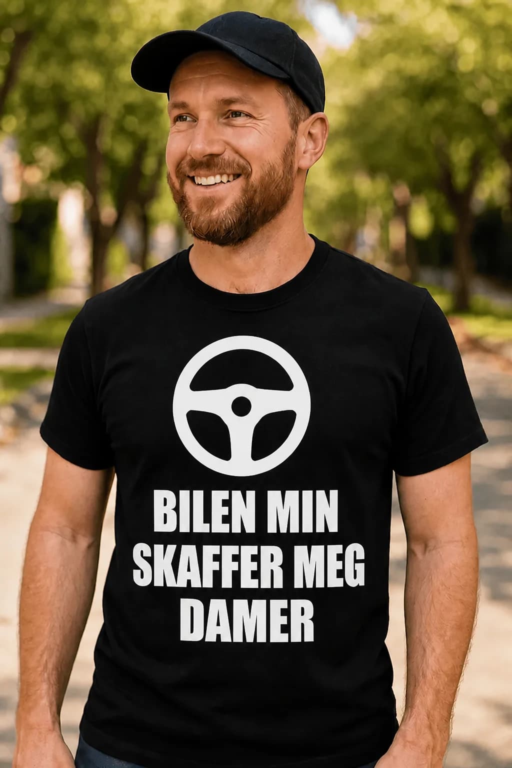 Smilende mann i caps og svart morsom t-skjorte til bilentusiaster med ratt og tekst om bilen