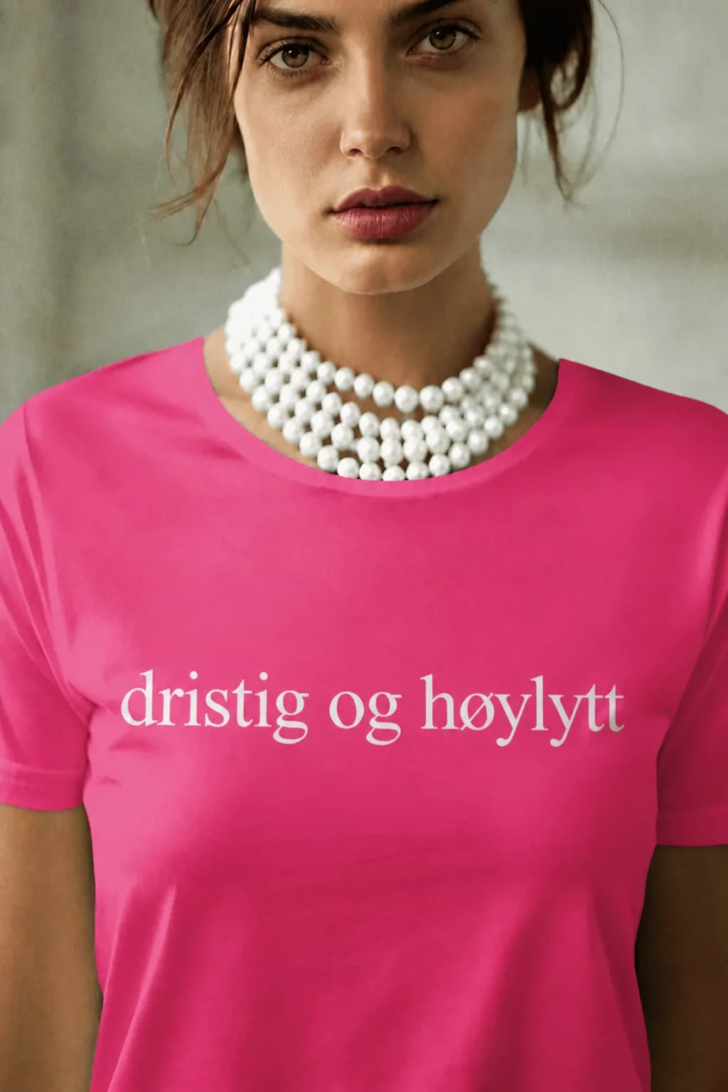 Kvinne med perlekjede i rosa morsom t-skjorte med den hvite teksten «dristig og høylytt»