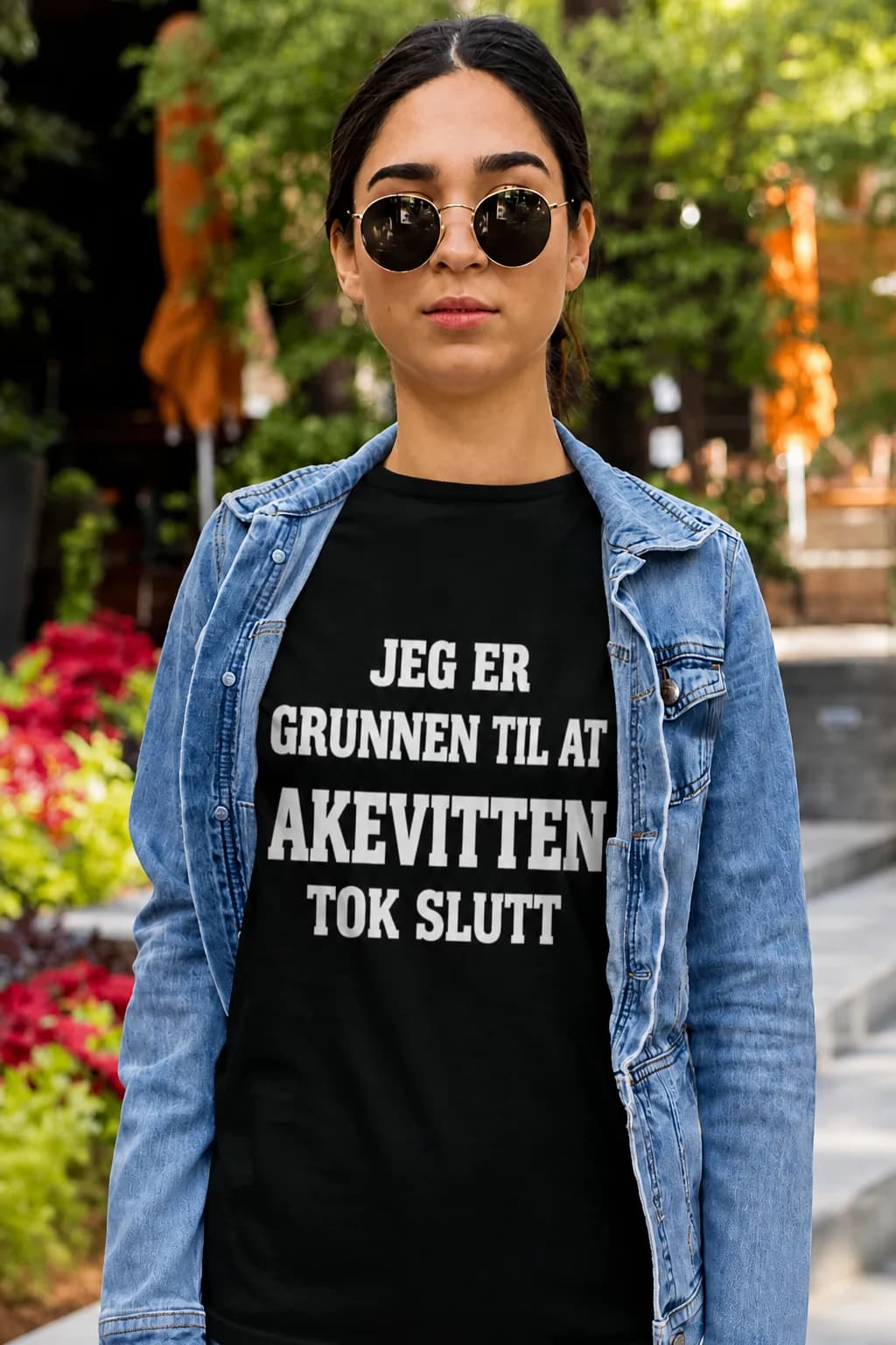 Kvinne i dongerijakke og svart morsom t-skjorte med hvit tekst om at hun er grunnen til at akevitten tok slutt