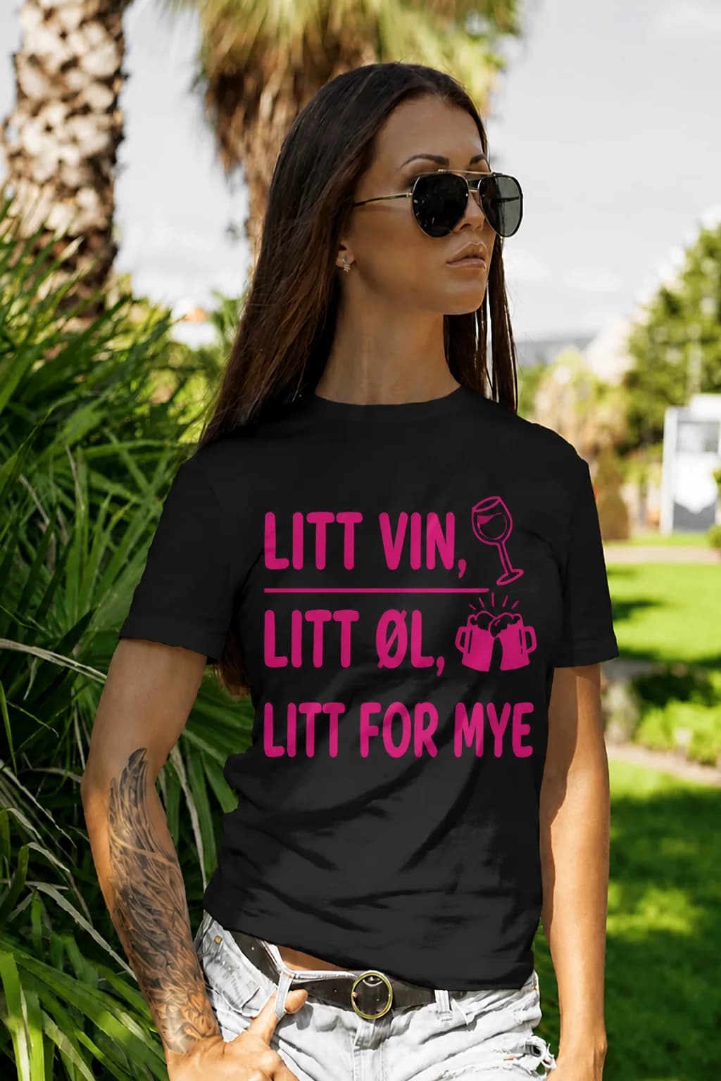 Kvinne i svart morsom t-skjorte med rosa tekst om vin og øl, et vinglass og to ølglass