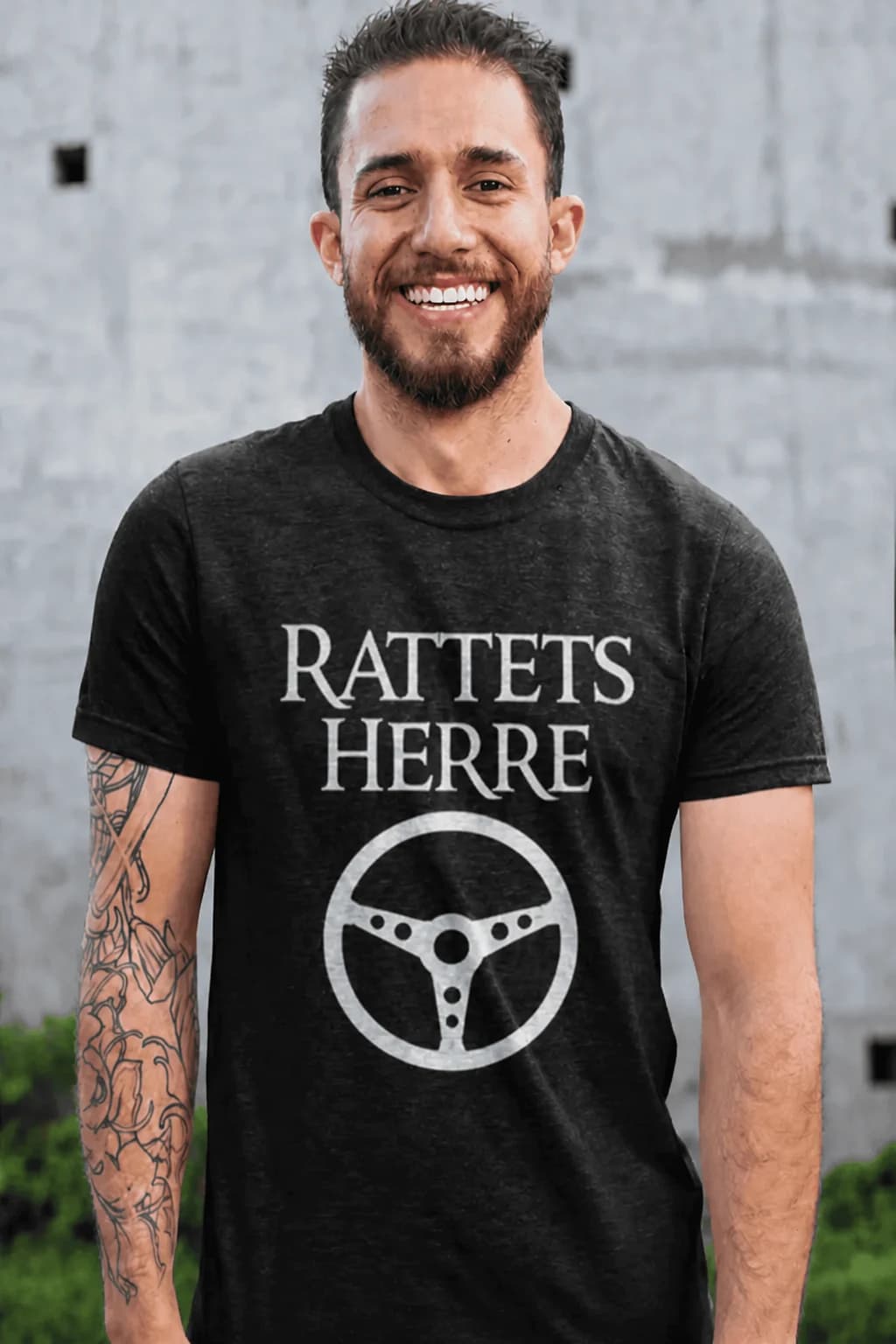 Smilende mann i svart bil-t-skjorte med teksten «Rattets herre» og et enkelt ratt under