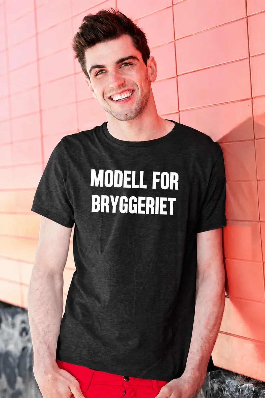 Smilende mann i mørk øl-t-skjorte med hvit tekst om at han er modell for bryggeriet