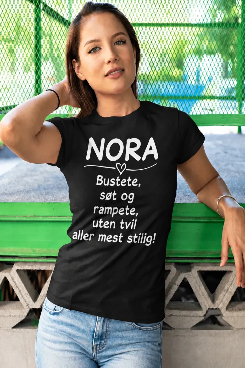 Kvinne i svart t-skjorte med navn, hjerte og teksten «Bustete, søt og rampete, uten tvil aller mest stilig!»