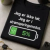 Gøy t-skjorte med teksten «Jeg er ikke lat. Jeg er i strømsparingsmodus.» med batteri på 5 prosent og trøtt uttrykk i grønn og hvit design på mørk bakgrunn.