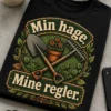 T-skjorte med teksten «Min hage. Mine regler.» og et robust hagemotiv med kryssede spade og rake, slyngende blader og rustikk uttrykk.
